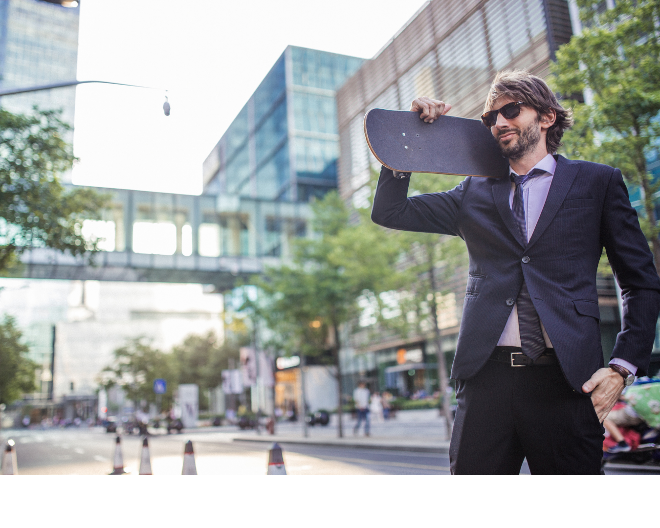 Homem de terno com skate no ombro em uma rua da cidade.