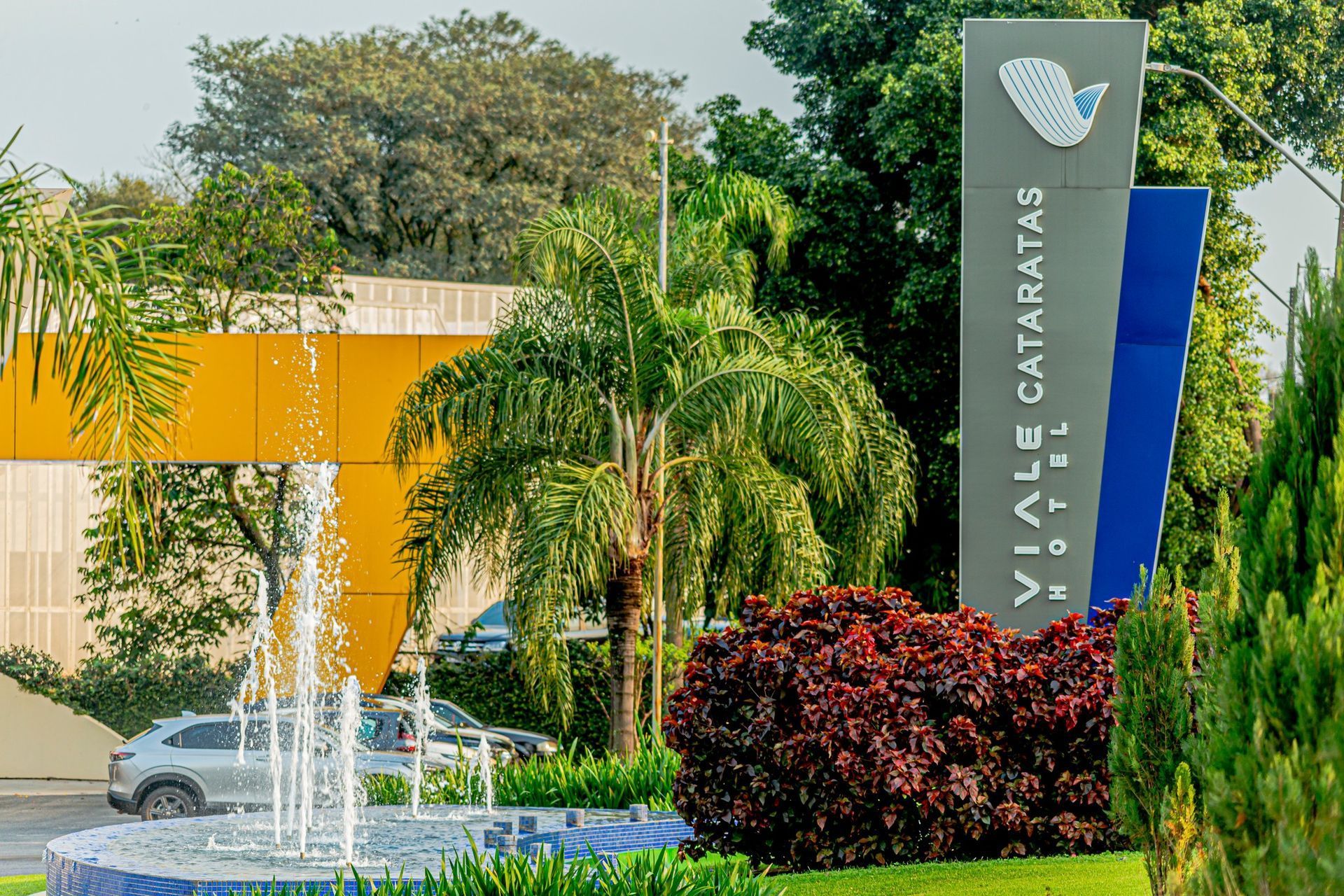 Placa do Viale Cataratas Motel, com fonte e paisagismo colorido.