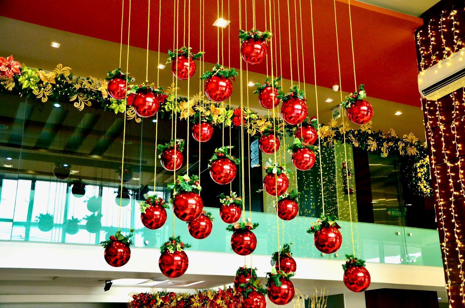 Enfeites vermelhos com folhagens pendurados em fios dourados decoravam o espaço interior.