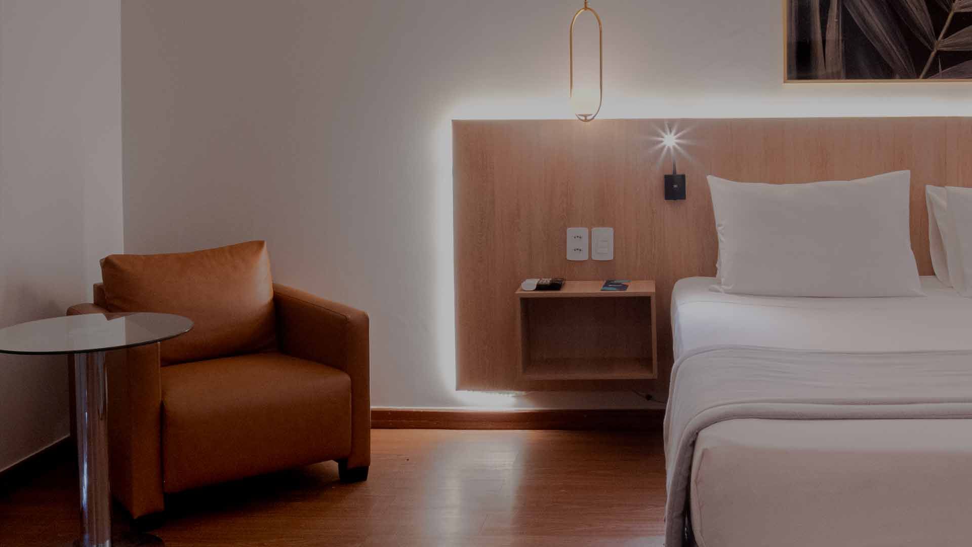 Edifício alto e moderno com fachada de vidro azul e uma grande cobertura circular de entrada contra um céu claro.