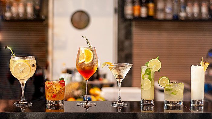 Coquetéis no bar: bebidas de limão, laranja, martini, mojito e abacaxi em copos.