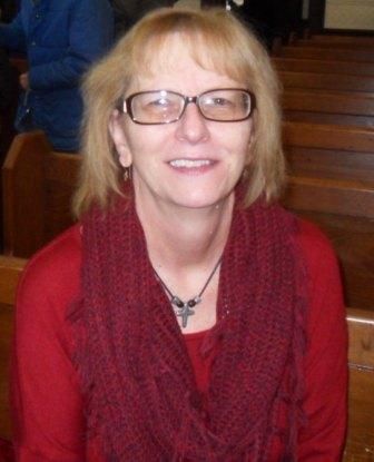 A woman wearing glasses and a red scarf is sitting in a church.