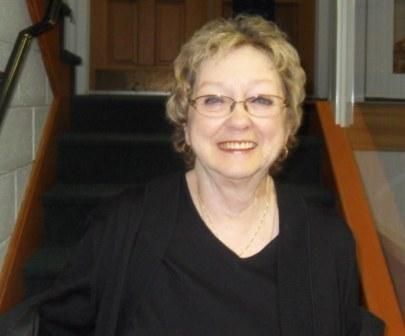 A woman wearing glasses is sitting on a set of stairs