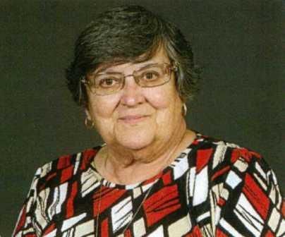 A woman wearing glasses and a red and black shirt is smiling for the camera.