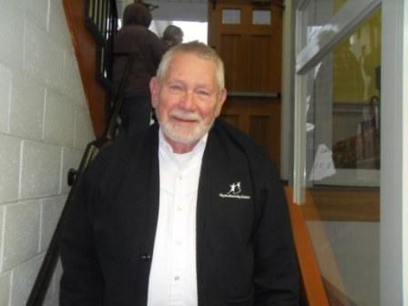 A man in a black jacket and white shirt is standing on a set of stairs.