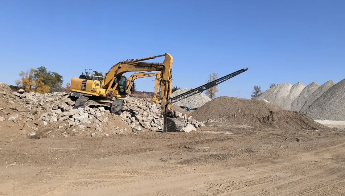 A large yellow excavator is sitting on top of a pile of dirt.
