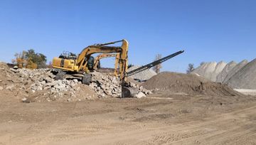 A large yellow excavator is sitting on top of a pile of dirt.
