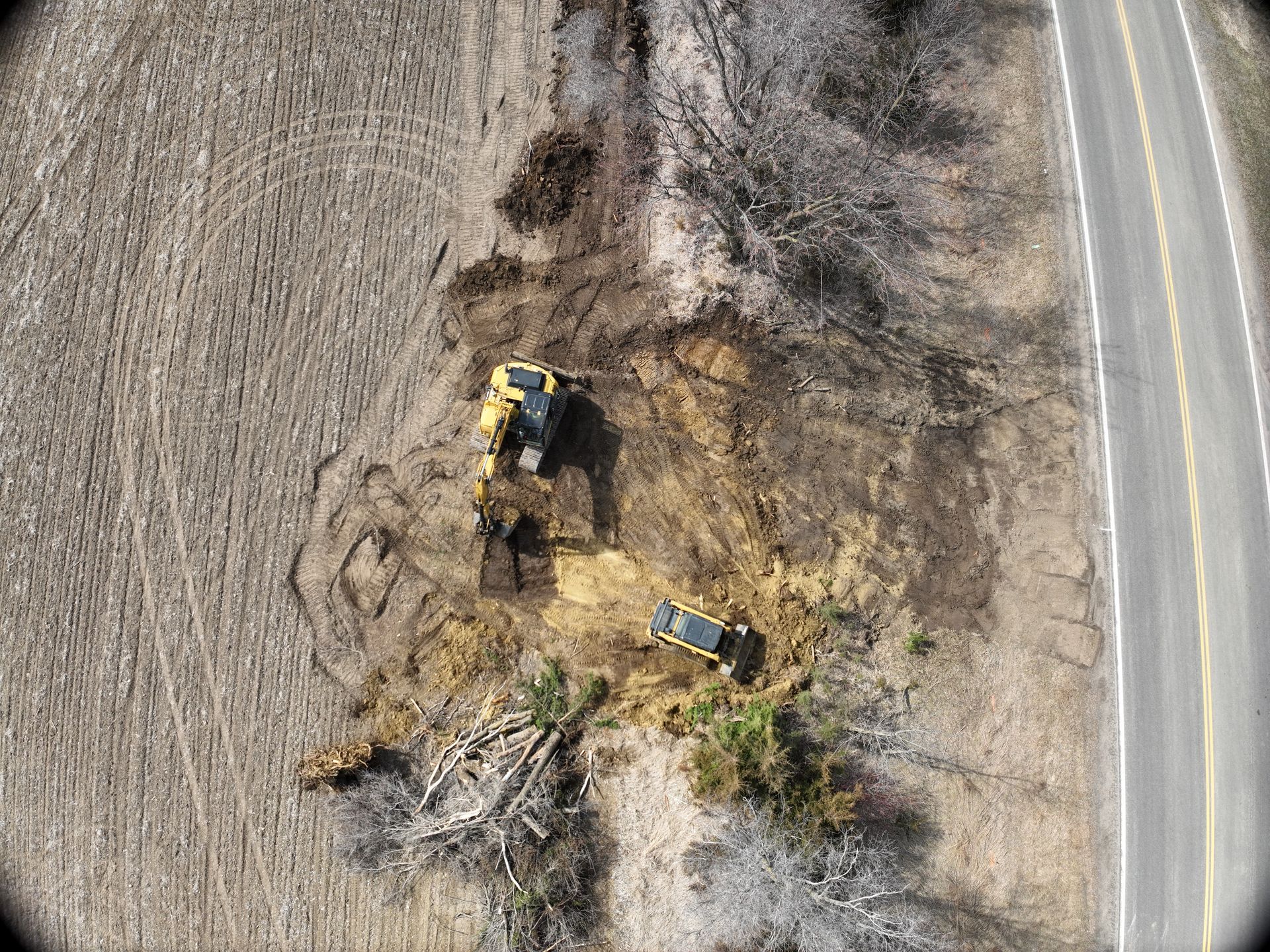 A yellow excavator is digging in the dirt in a field.