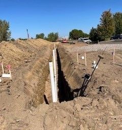 A crane is lifting a pipe into a trench.