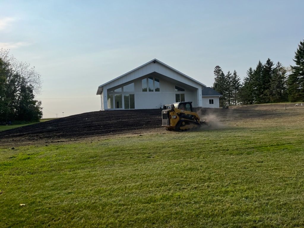 A bulldozer is moving dirt in front of a large white house.