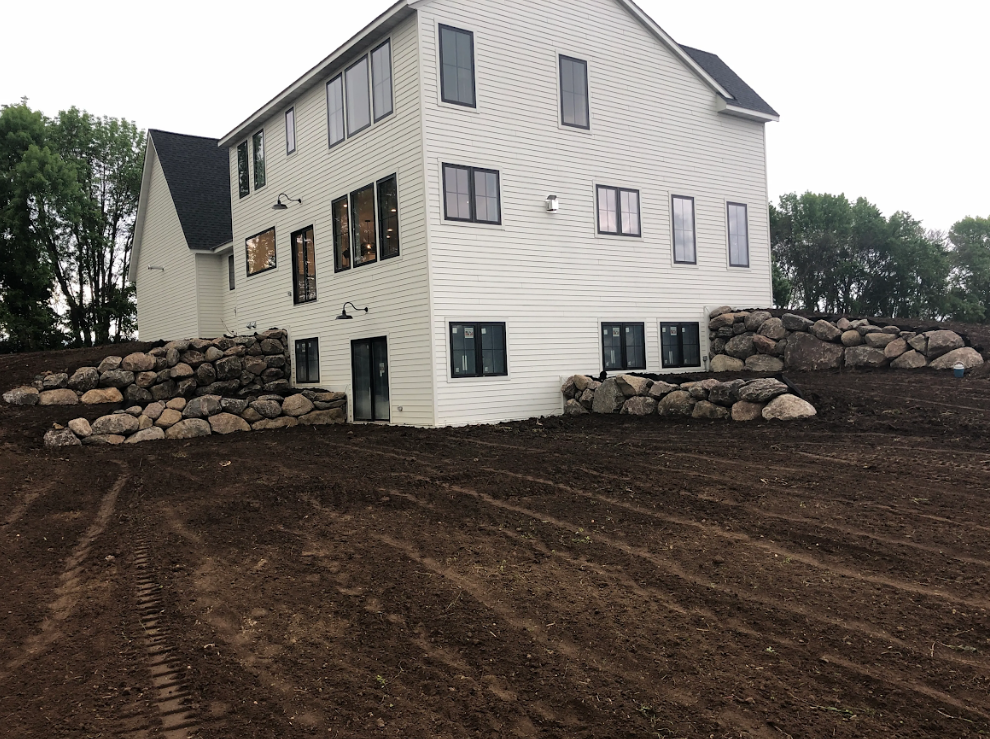 A large white house is sitting on top of a dirt hill.