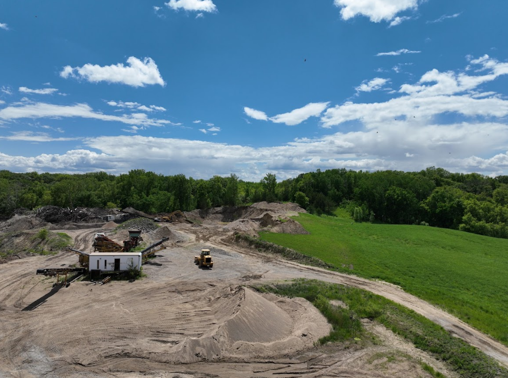 An aerial view of a dirt field with a house in the middle of it.