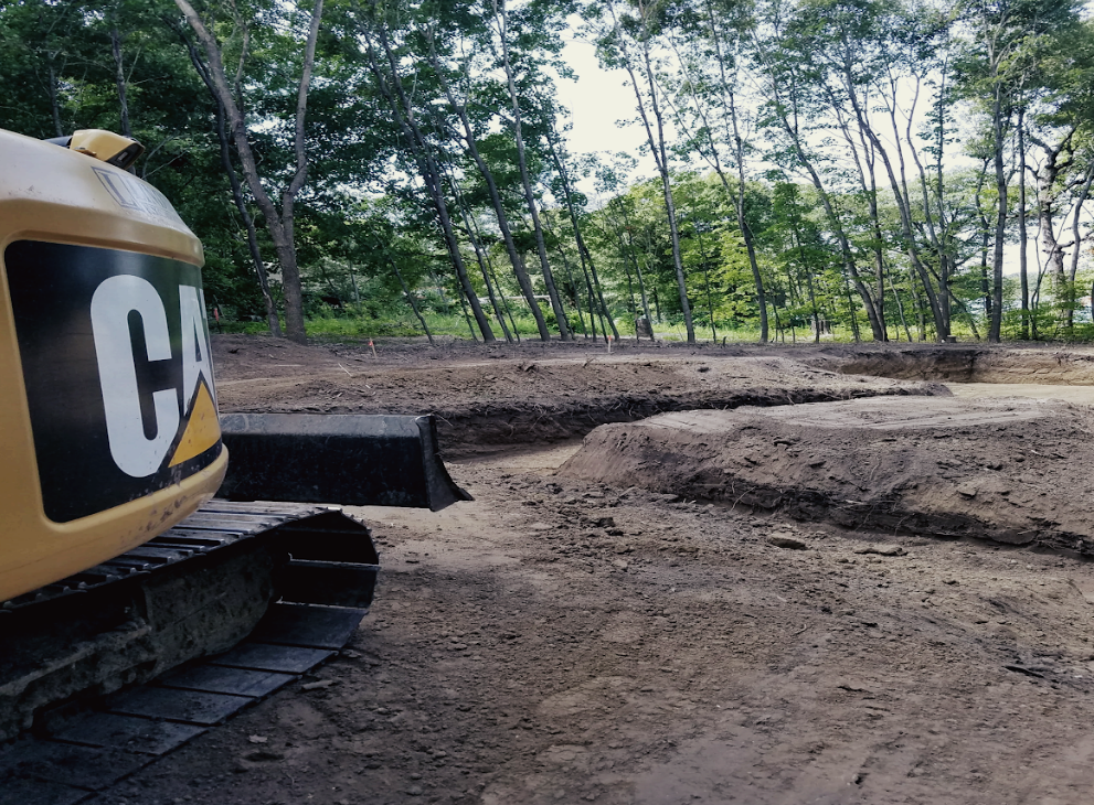 A cat excavator is parked in a dirt field