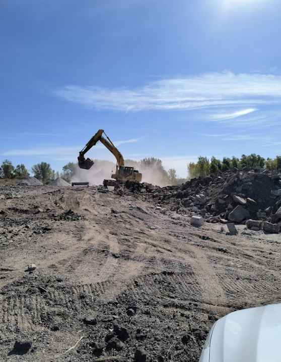 A large excavator is working on a dirt road