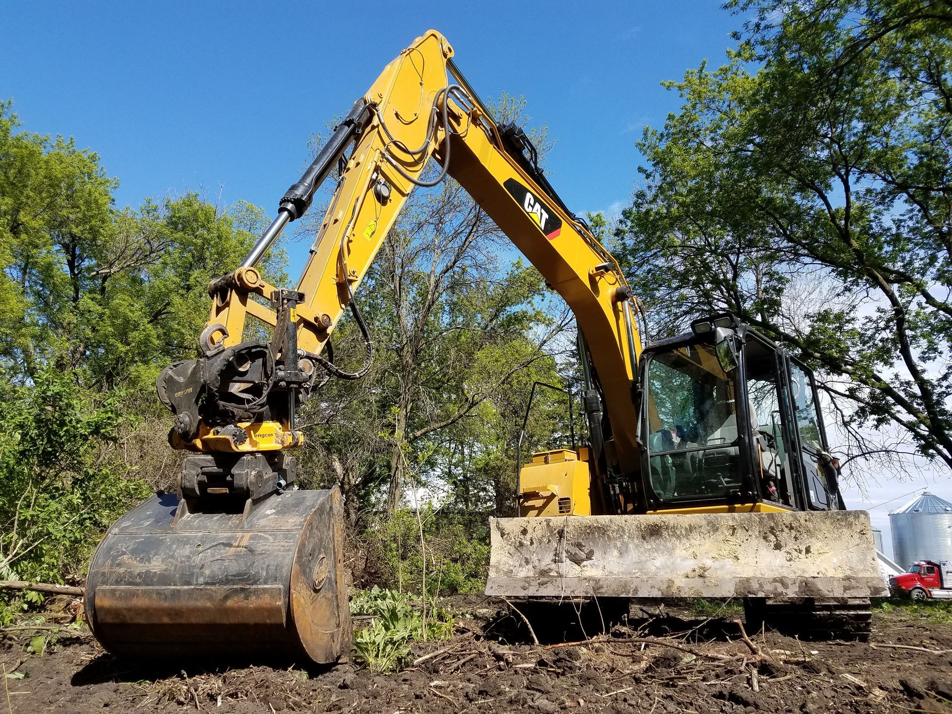 A yellow excavator is digging in the dirt in a field.
