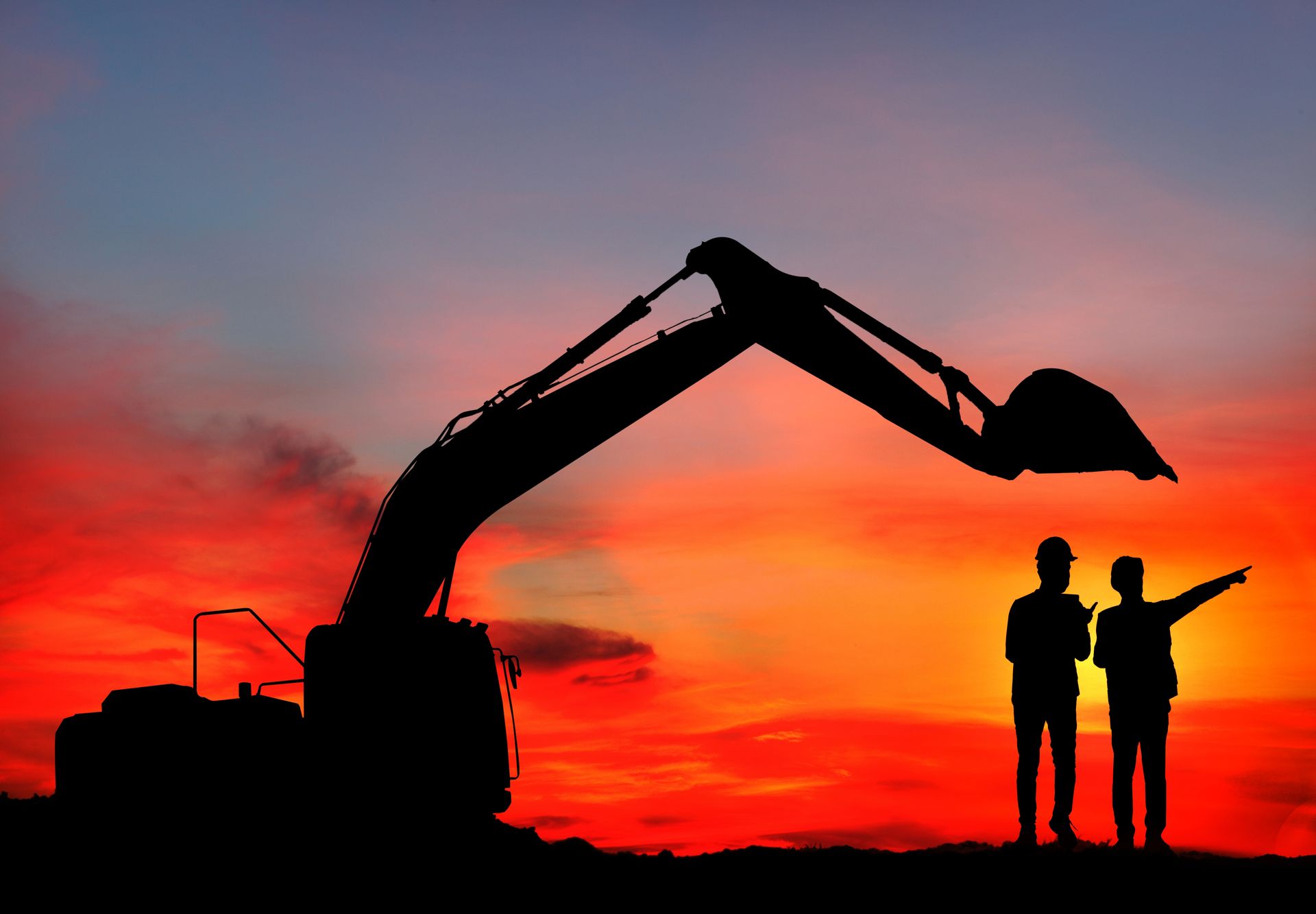 Two men are standing in front of an excavator at sunset.