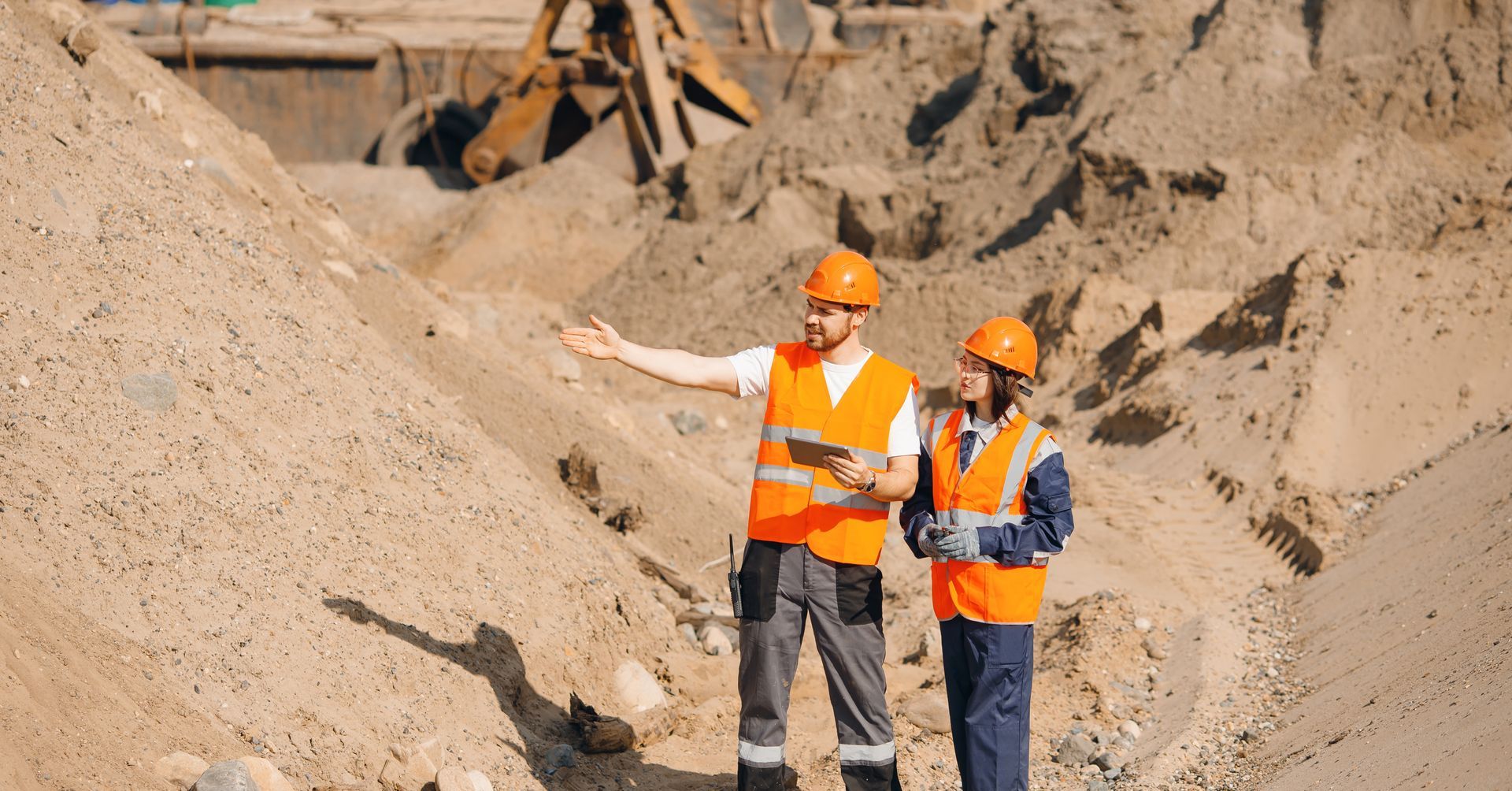 A man and a woman are standing in front of a pile of dirt.