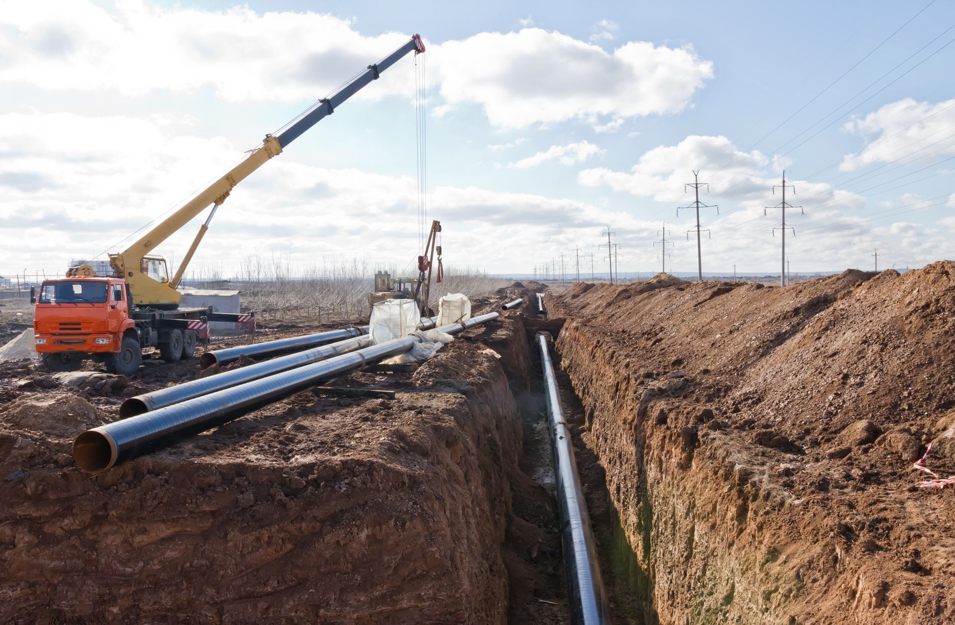 A crane is lifting a pipe into a trench.