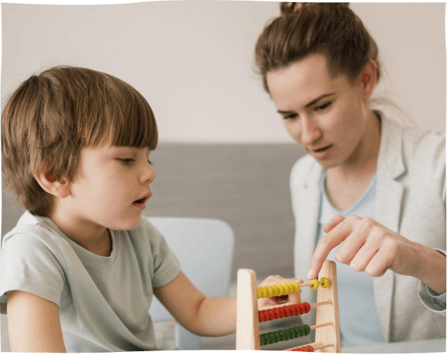 A woman is teaching a young boy how to use an abacus.