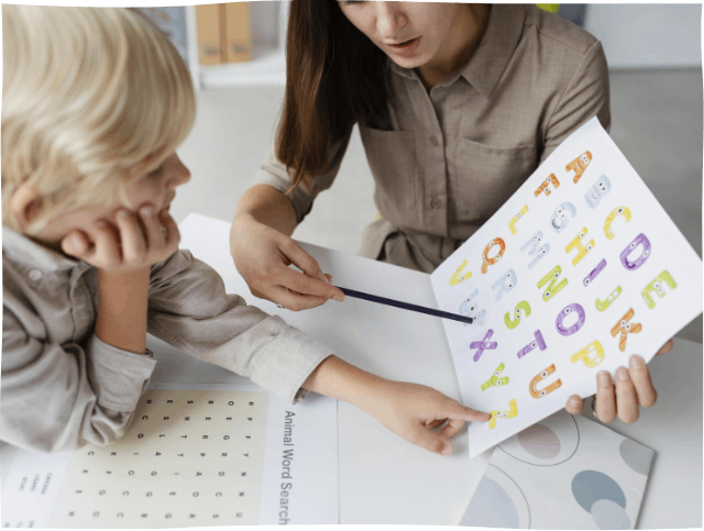 A woman is teaching a child how to read the alphabet