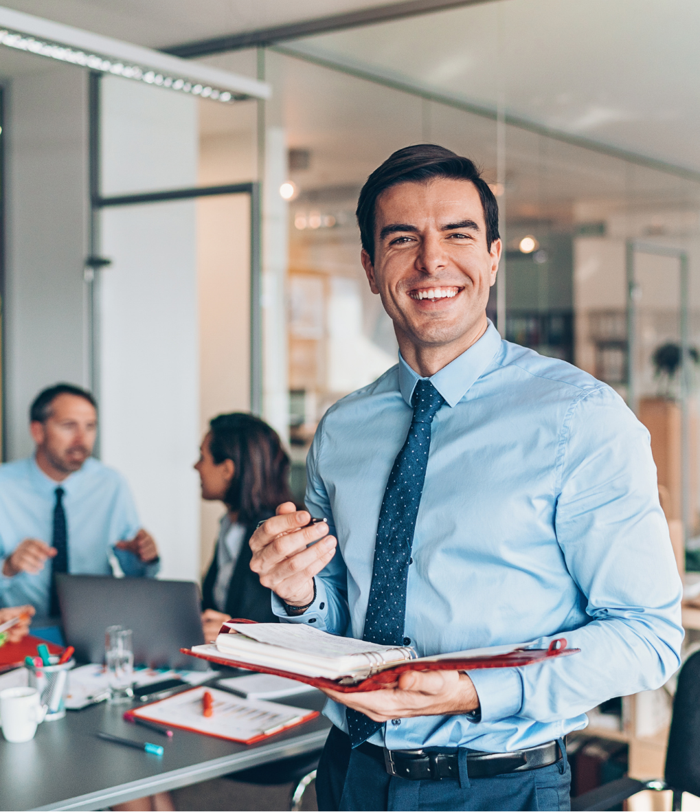 a man in a blue shirt and tie is holding a clipboard and smiling .