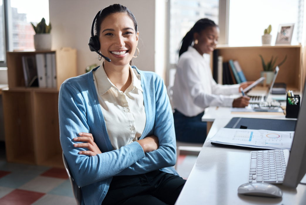 a woman wearing a headset is sitting at a desk in an office.
