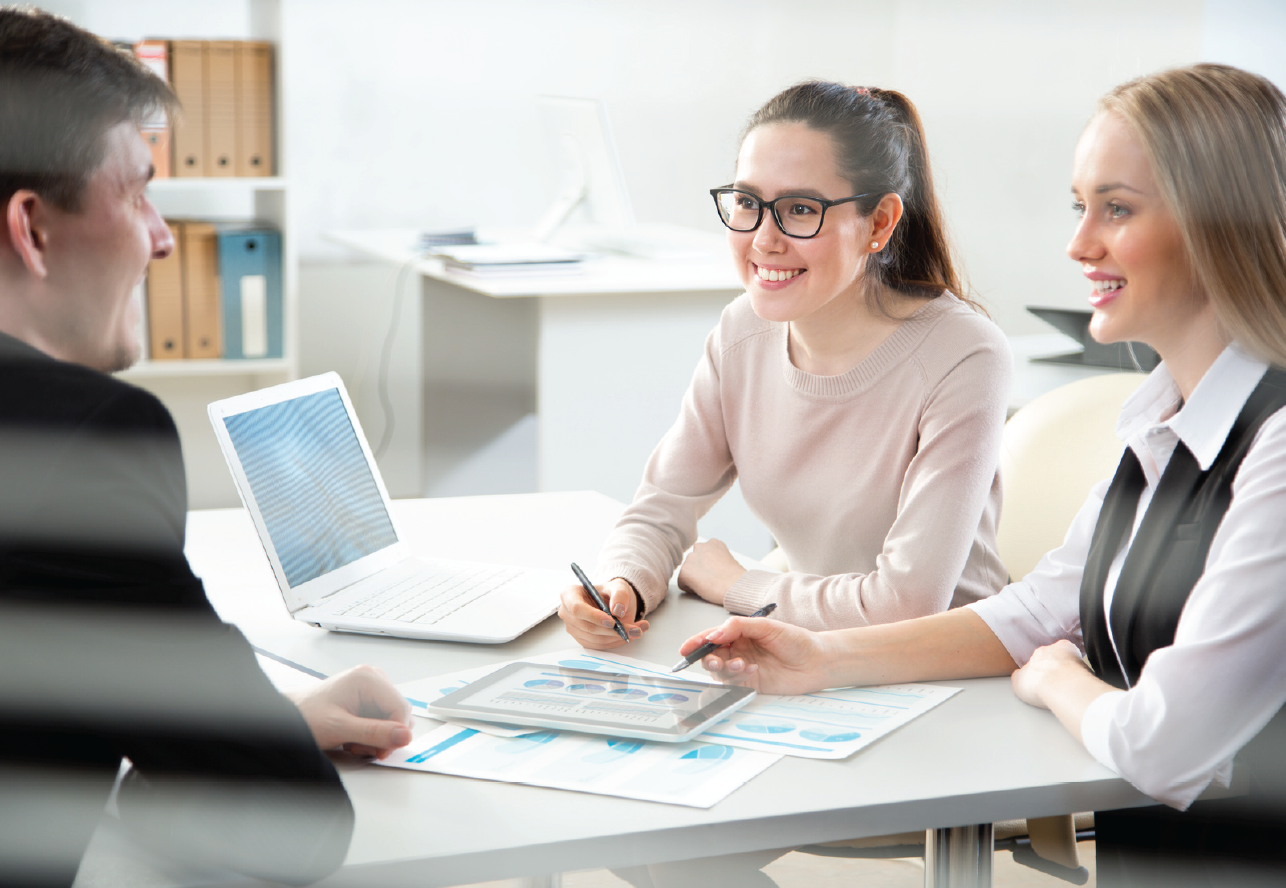 a group of people are sitting at a table having a meeting .