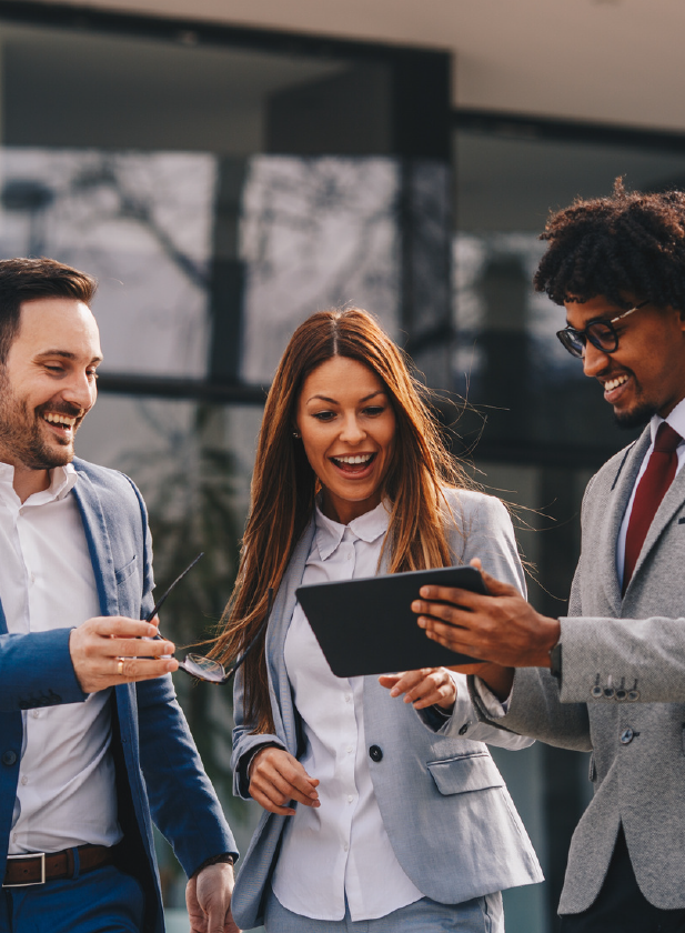 a group of business people are standing next to each other looking at a tablet .