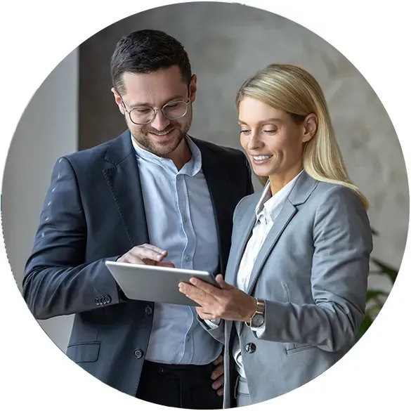 Men and women are standing in the office and looking at a tablet.
