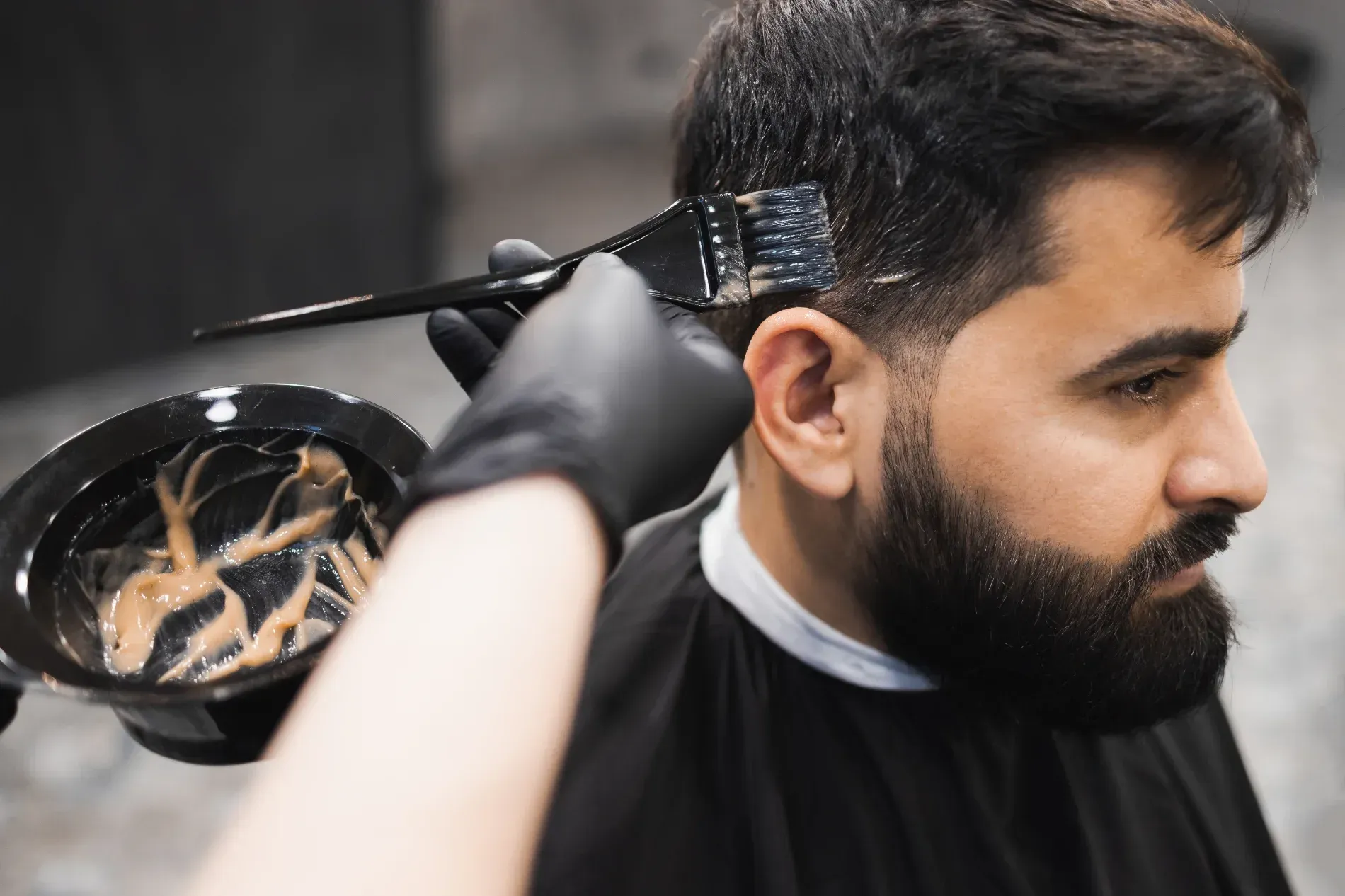 Hair stylist applying dye to a man's hair in a salon — The Gentleman's Barber QLD in Toowoomba City, QLD