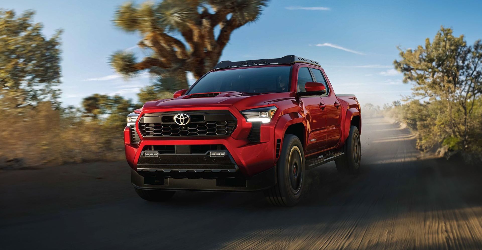 Un camión rojo circula por un camino de tierra.