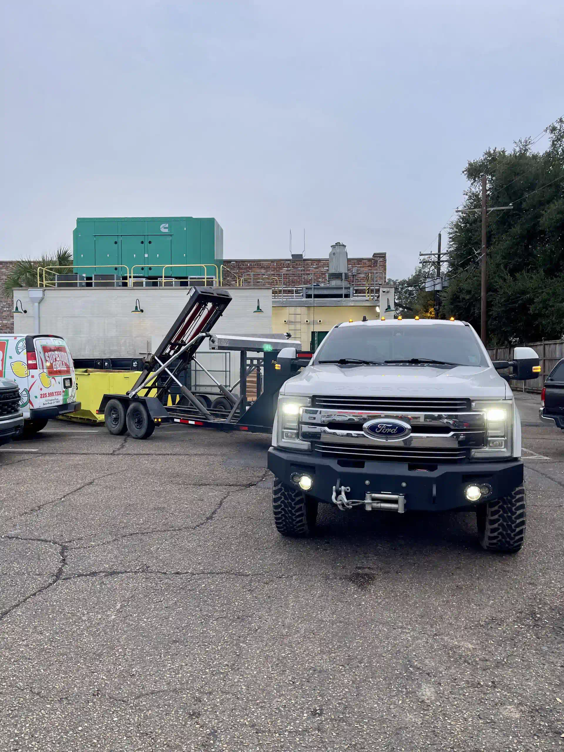 A white truck is parked in a parking lot next to a trailer.