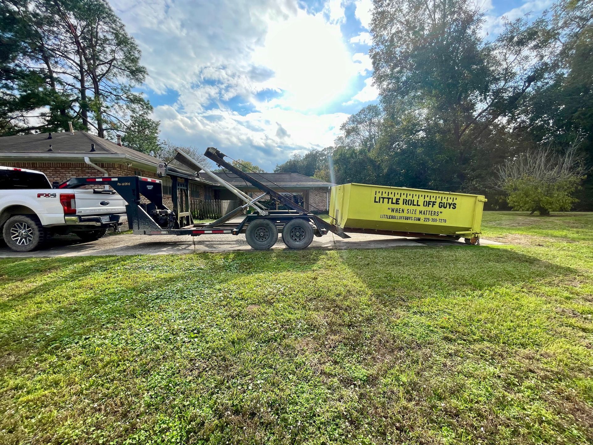 A dumpster on a trailer is parked in front of a house.