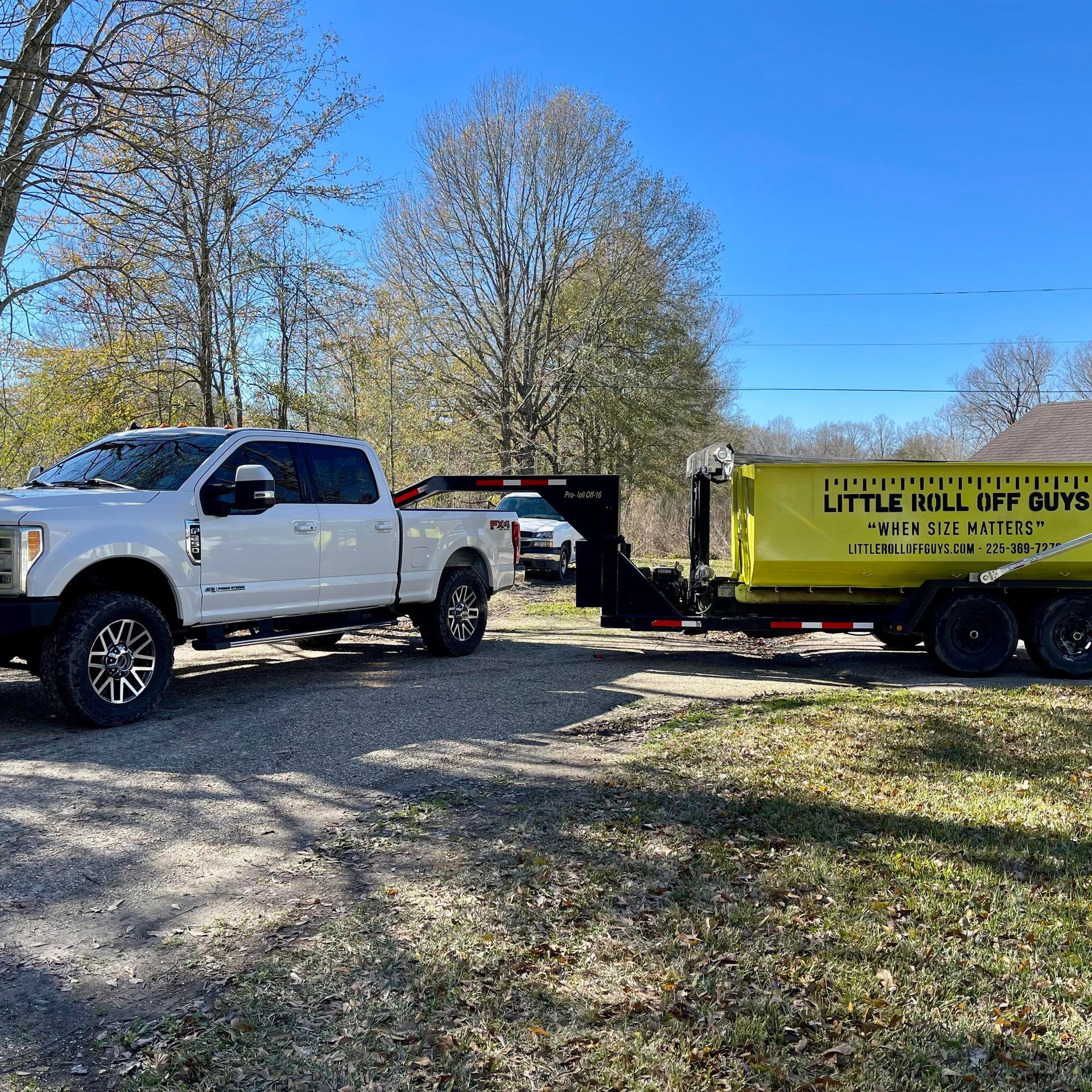 A white truck is parked next to a yellow dumpster.