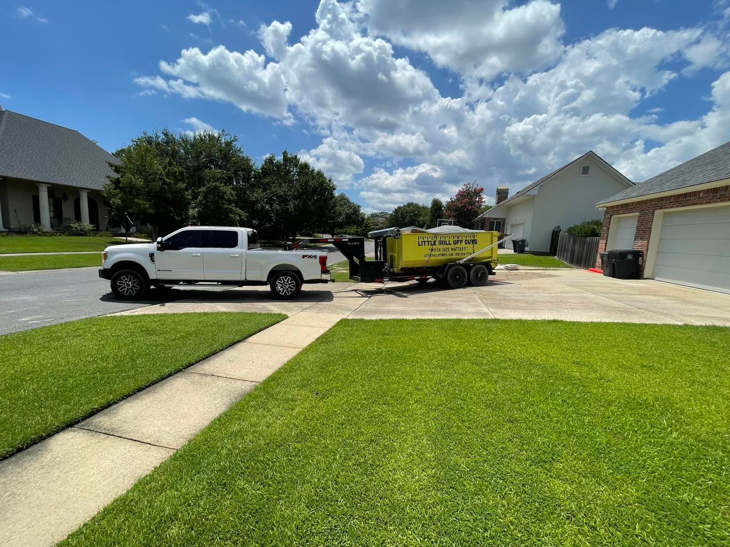 A white truck is parked in a driveway next to a yellow trailer.
