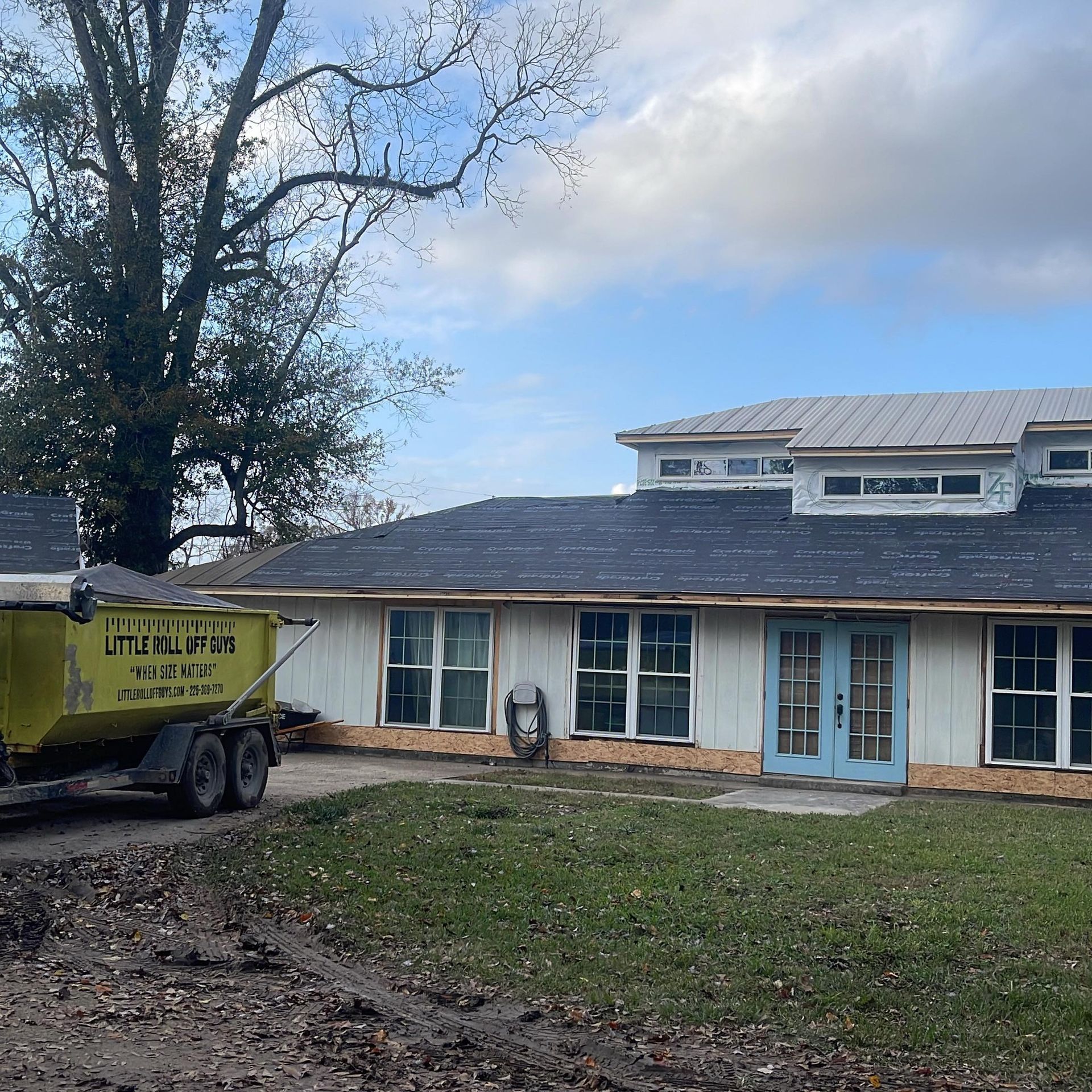 A yellow dumpster is parked in front of a house