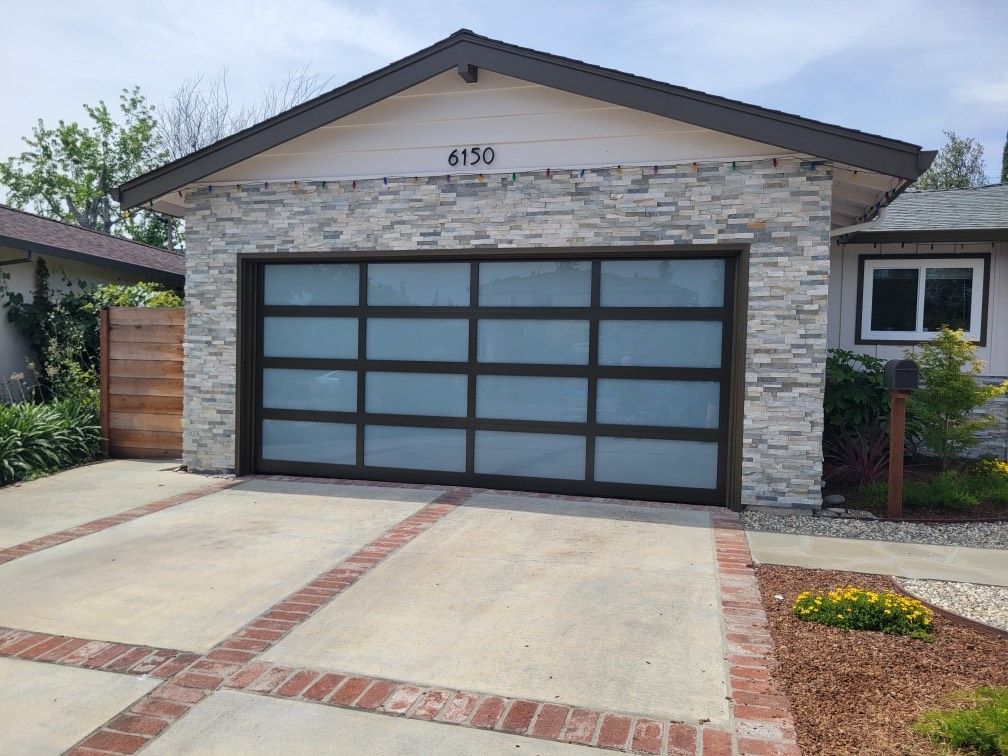 A house with a large garage door and a brick driveway.