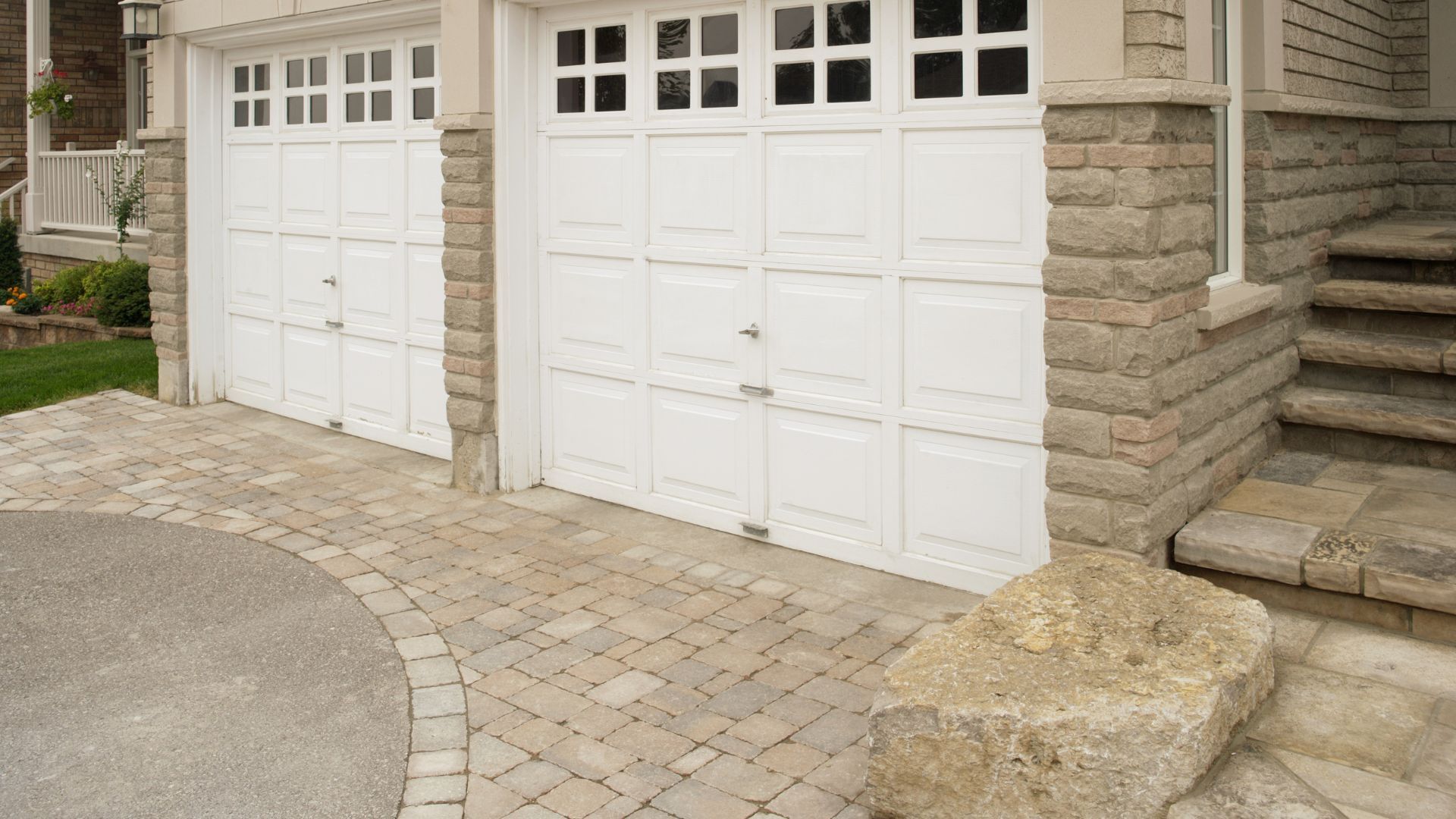 Two white garage doors are sitting next to each other on the side of a house.