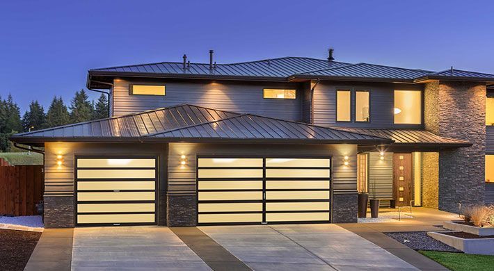 A large house with two garage doors is lit up at night.