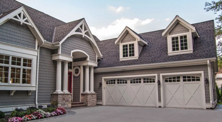 A large house with three garage doors and a large driveway.