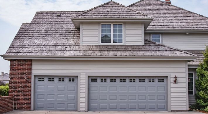 A large house with two garage doors and a shingle roof.
