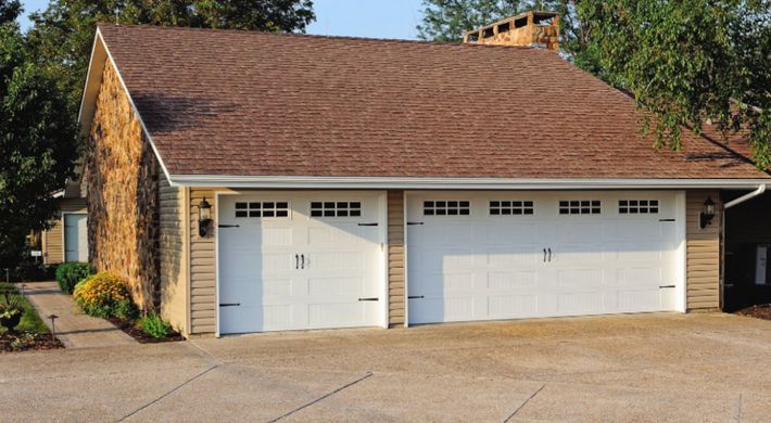 A house with three garage doors and a brown roof