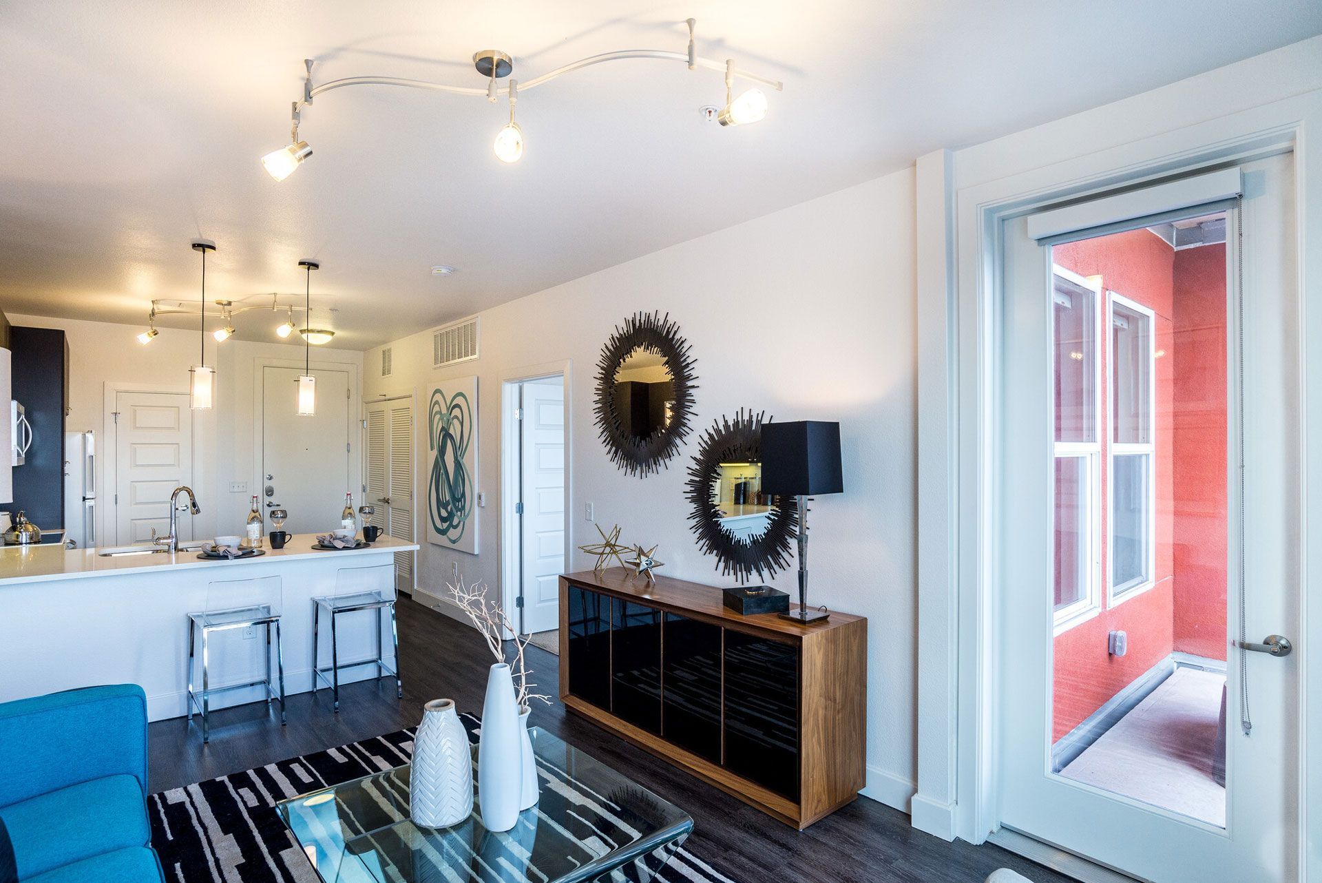 Open-concept living area with kitchen island, contemporary decor, and a glass coffee table.