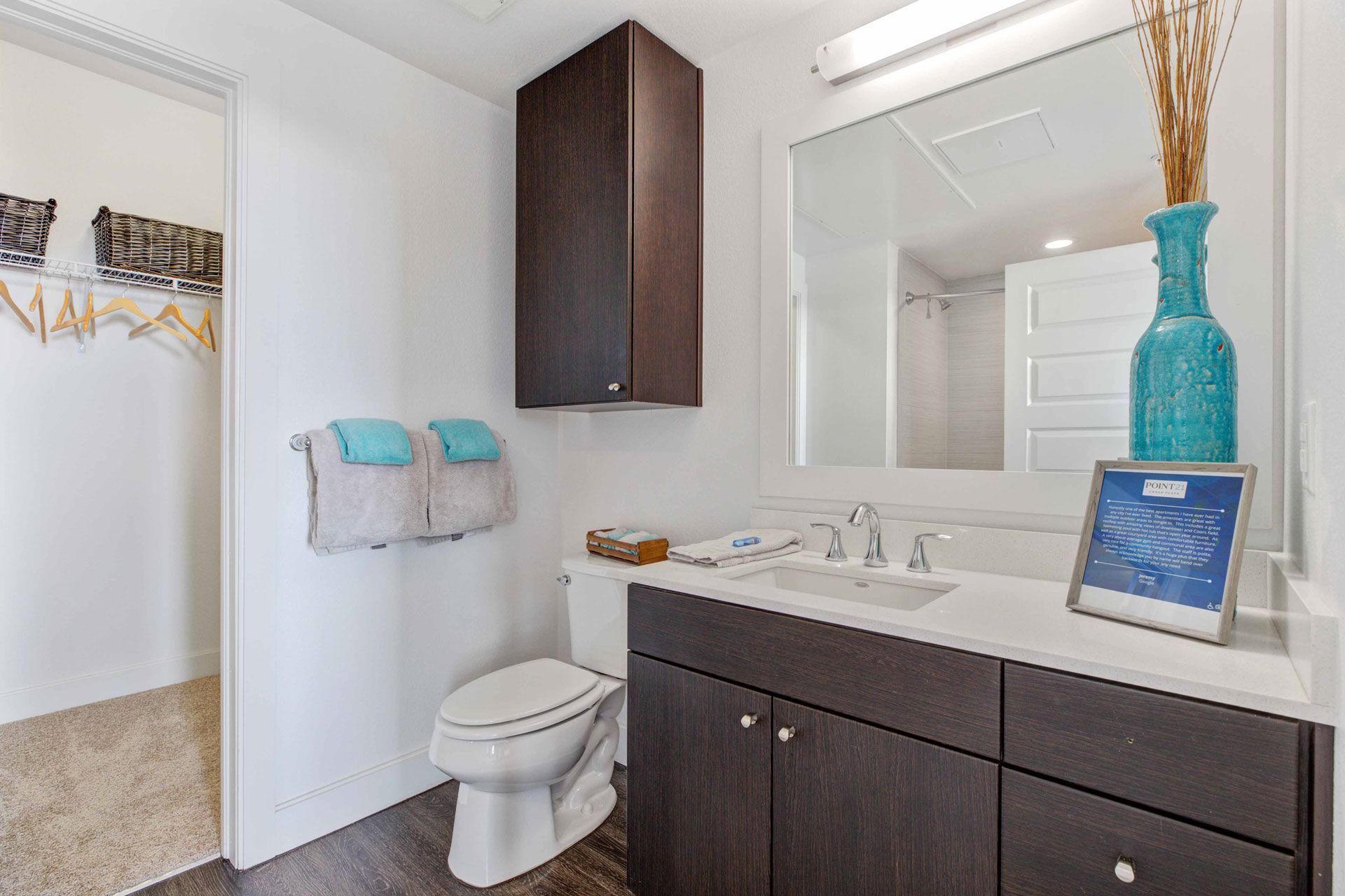 Bathroom with dark wood vanity, sink, large mirror, towels, and a toilet.