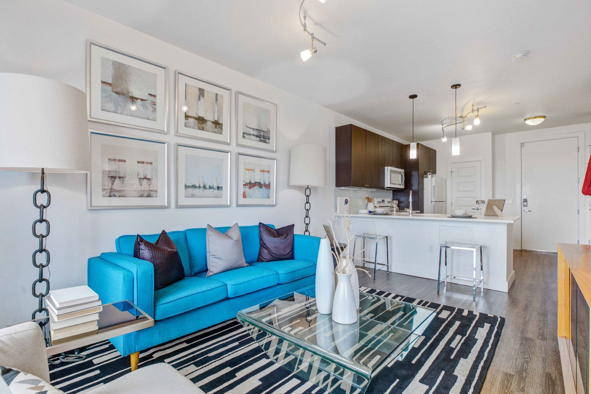 Bright modern living room with a blue sofa and open kitchen in an apartment.