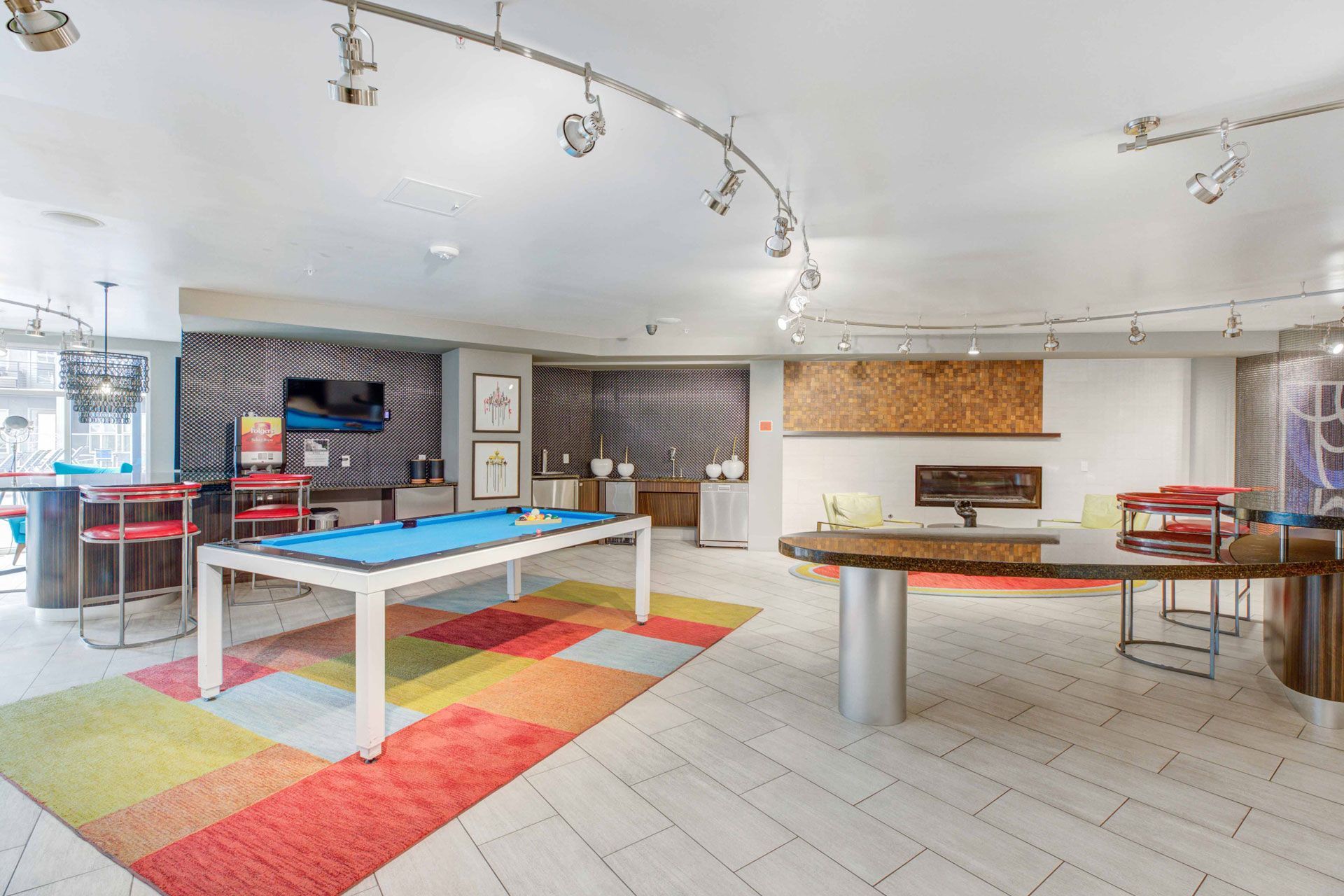 Indoor community lounge with a pool table, bar seating, and a fireplace.