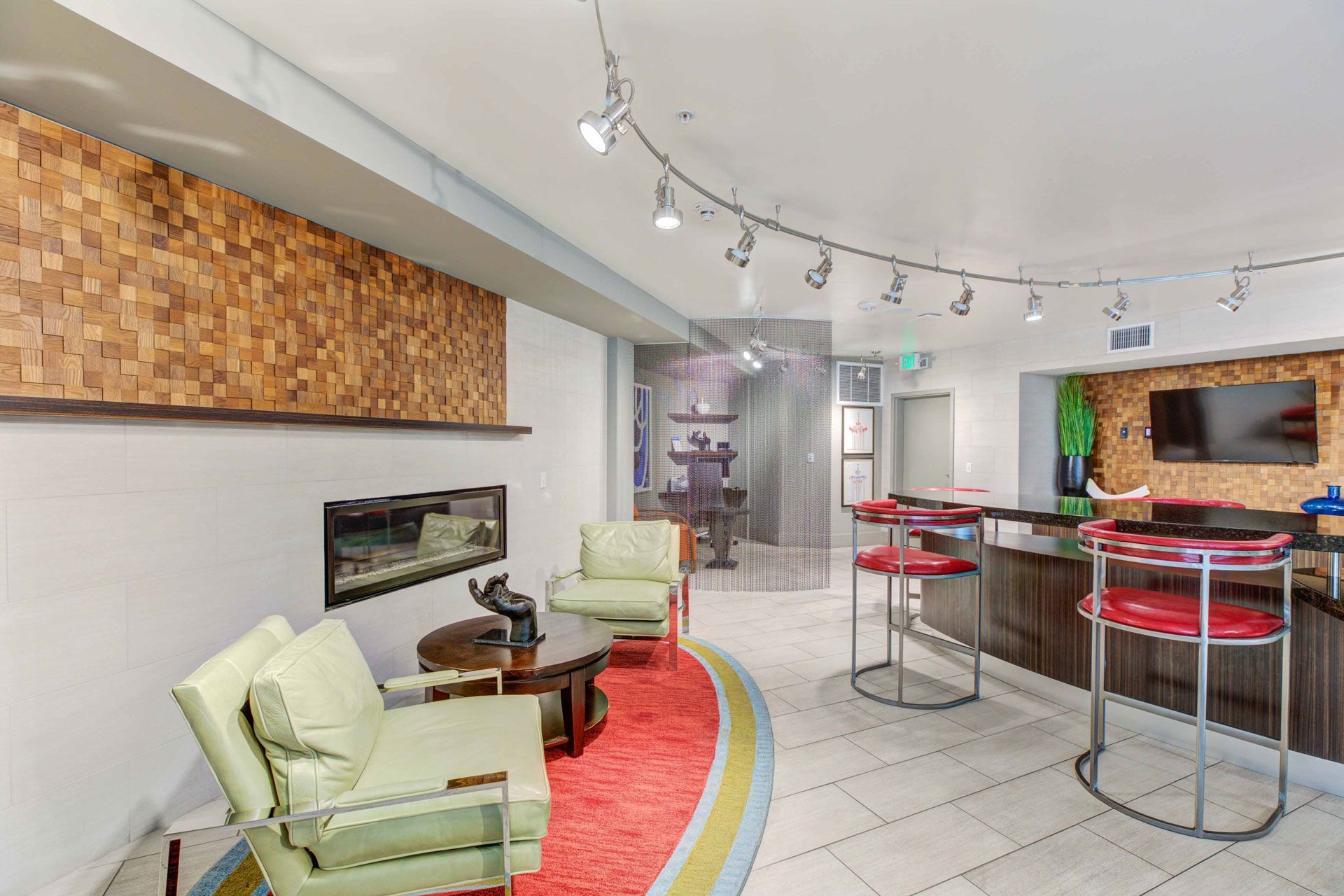 Modern apartment community lounge with seating, curved bar, and wall TV.
