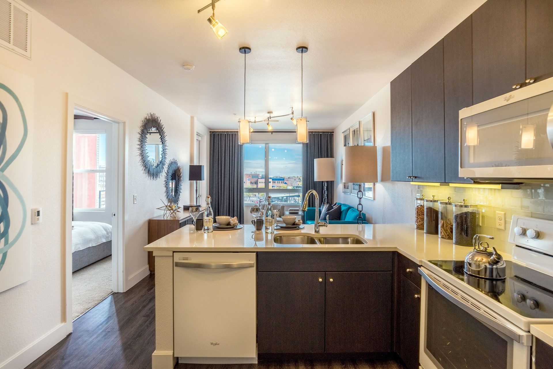 Open-concept kitchen with an island, dark cabinets, stainless appliances, and a view to the living area.