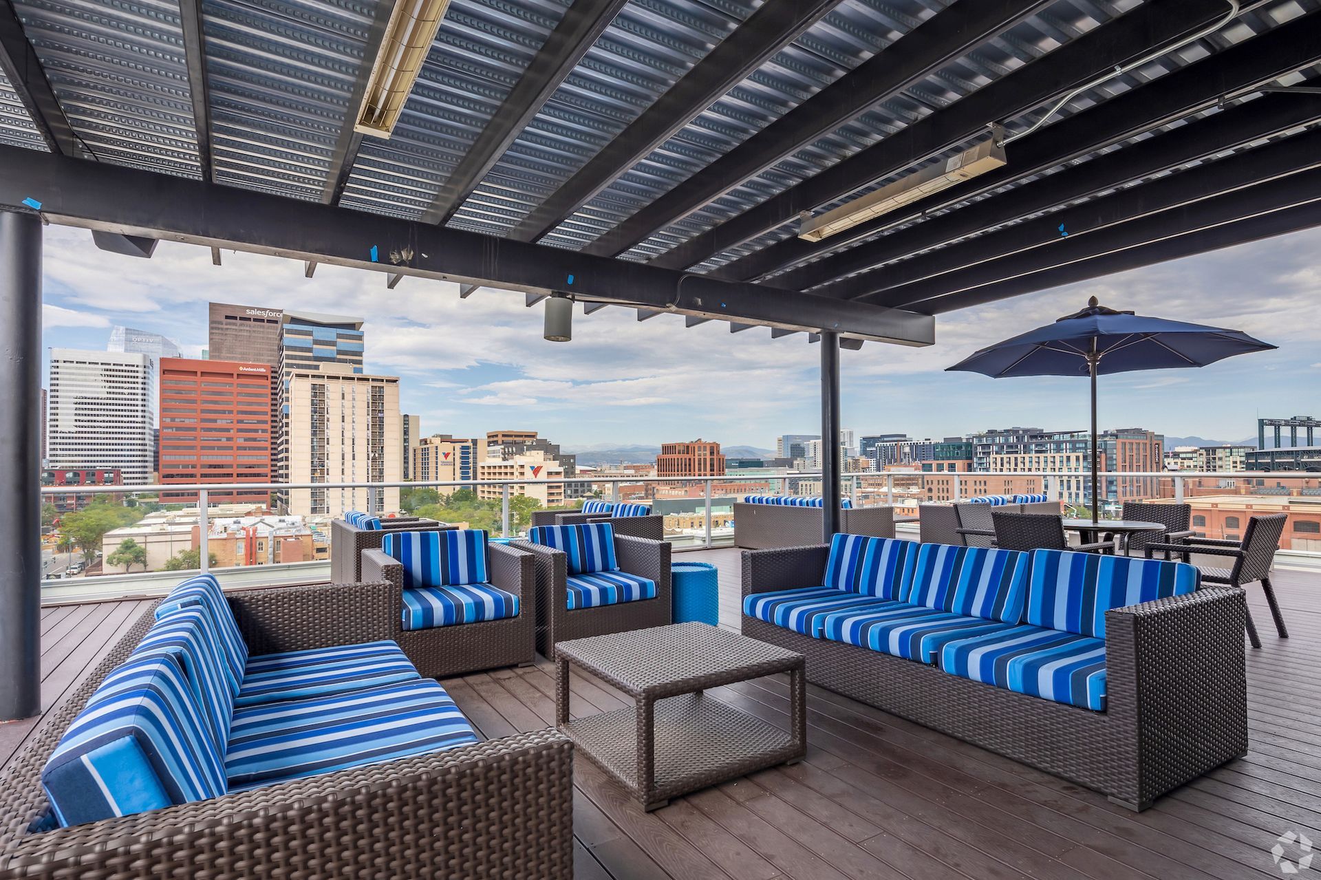 Rooftop lounge with blue-striped cushioned seating and a city view.