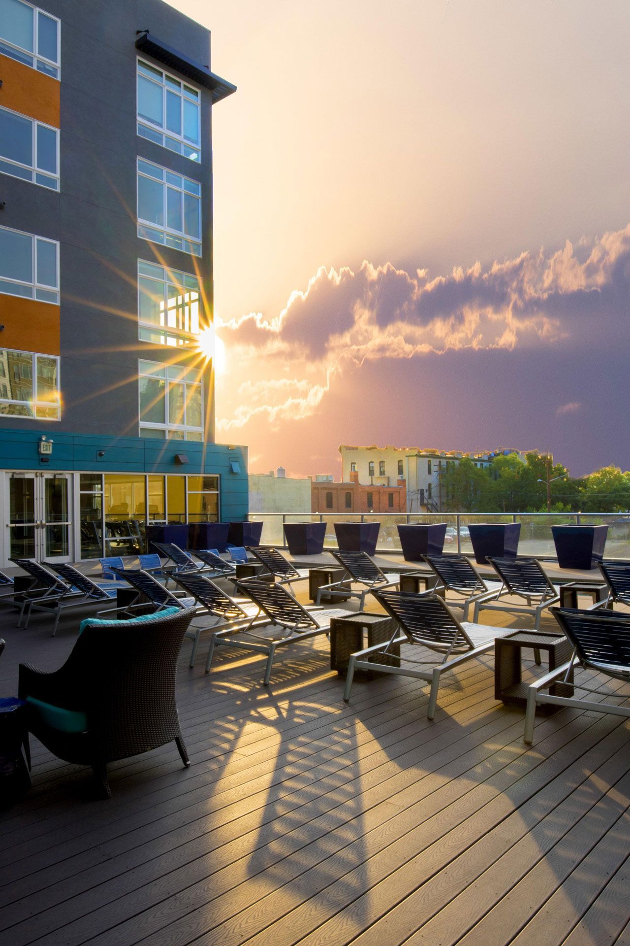 Rooftop terrace with lounge chairs on a modern apartment building at sunset.
